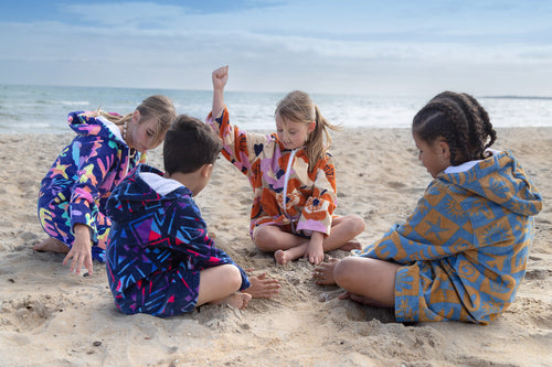 kids playing on beach wearing colourful printed towel jackets