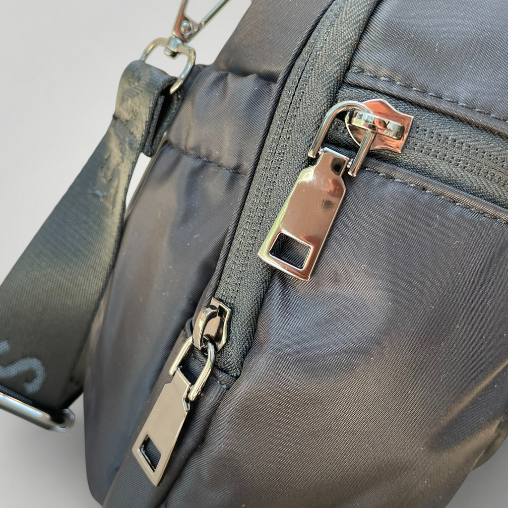 Black drink bottle carry bag, showing metal zip pocket details.